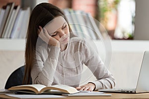 Exhausted young girl falls asleep during preparation for final examination.