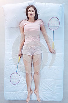 Exhausted young lady having rest with badminton rackets