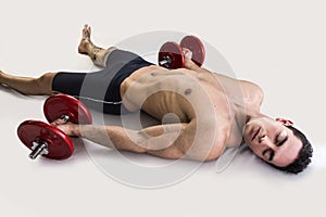 Exhausted young male bodybuilder resting on floor