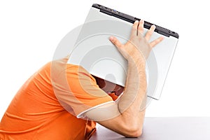 Exhausted young man covering his head with his laptop
