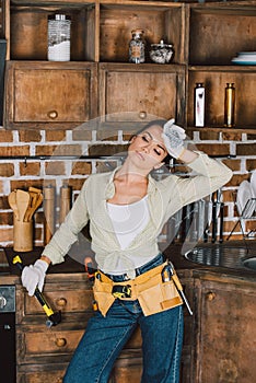 exhausted young repairwoman with hammer