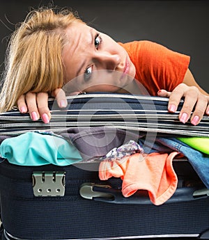 Exhausted young woman packing luggage