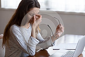 Exhausted young woman taking off glasses, suffer from eyes strain.