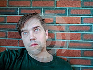 Exhausted, Zombified, Young Man Leaning Against Brick Wall