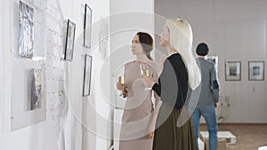 Exhibition in an art gallery. Art connoisseurs inspect the abstract works of a contemporary artist. Men and women spend