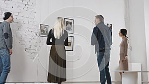 Exhibition in an art gallery. Art connoisseurs inspect the abstract works of a contemporary artist. Men and women spend