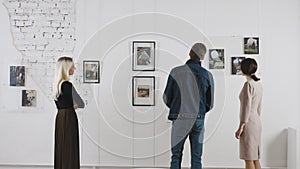 Exhibition in an art gallery. Art connoisseurs inspect the abstract works of a contemporary artist. Men and women spend