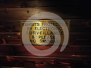 Exhibits protected by electronic surveillance and please no smoking sign on wood