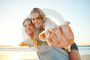 Exhilarated by love. a young man giving his girlfriend a piggyback ride at the beach.