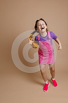 Exhilarated radiant happy female child having fun with two kanekalon pigtails of yellow color dressed in pink jumpsuit