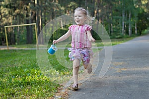 Exhilarated running girl on asphalt park footpath holding package of sidewalk chalks