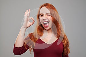 Exhilarated woman making ok gesture and winking