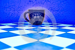 Dark cup on blue chess board and blue abstract background