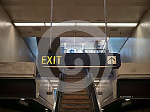 Exit sign in a dark tunnel with stairs leading up