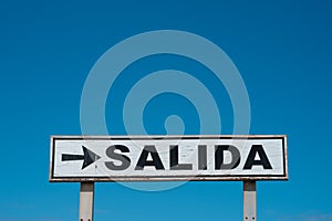 Exit sign spanish: SALIDA on blue sky - photo