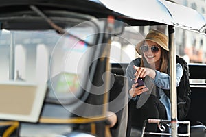 Exited caucasian woman tourist with sunglasses sitting in back seat of Tuk Tuk public transport in Thailand