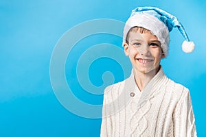 Exited child in blue Santa hat waiting Christmas time or presents on blue background with copy space. Mockup. Generation