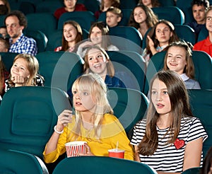 Exited little girls watching movie in the cinema hall.