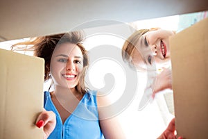 Exited mother and cute little daughter looking inside carton box