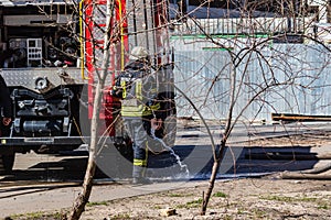 After exiting the fire, a firefighter douses his shoes with cold water near a firefighter of a special car.