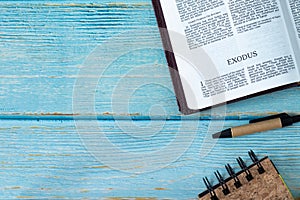 Exodus Bible Book on a wooden table with pen and notebook with copy space for text