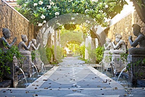 Exotic Bali scenery passage with traditional architecture, fountains, sculpture, gate and foliage