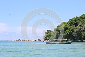 Exotic boat saling on clear beautiful beach island under the blue sky photo