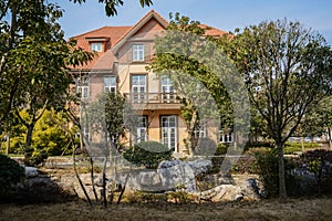 Exotic building behind rocks and trees at sunny winter noon