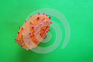 Exotic fruit of Cucumis metuliferus, African cucumber on a green background. Closeup, soft focus