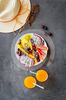 Exotic fruit salad in white plate. Fruits with fresh juice and hat, top view