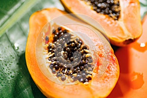 Exotic fruits background. Papaya orange fresh fruits on tropical leaf green background. Halved fresh organic Papayas