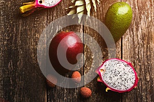 Exotic fruits on wooden background. Fresh dragon fruit, avocado, pineapple, lychee, mango at table. Fruit diet concept. Healthy