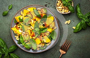 Exotic gourmet salad with juicy sweet peach, hot jalapeno peppers, salted peanuts and green basil, rustic green table background,