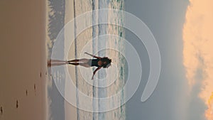 Exotic model posing waves cloudy evening vertically. Woman walking on wet sand