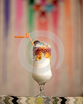 Exotic refreshing milkshake drink in glass goblet. Whipped milk and ice cream cocktail decorated with topping and straw