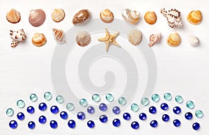 Exotic sea shells and glass beadson a white wooden background. Concept of summer travel and beach holidays. Flat lay, top view, co