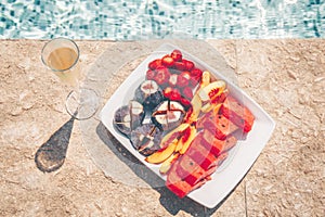 Exotic tropical fruit plate and glass of champagne on the pool edge