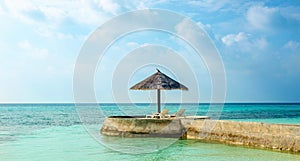 An exotic view of a palm tree umbrella on a cape overlooking the sea, Maldives