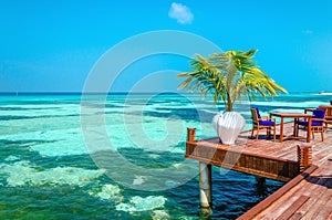 An exotic view of a wooden restaurant on stilts on a background of azure water and blue sky