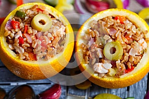 An exotically decorated dish of bulgur, poultry and vegetables with oranges. Two servings of colorful stew