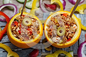 An exotically decorated dish of bulgur, poultry and vegetables with oranges. Two servings of colorful stew with spoons