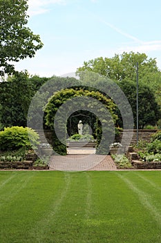 An expanse of grass leading to walled gardens and a courtyard with a statue in the sunken garden