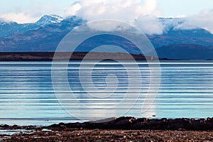 Expansive body of crystal clear blue water and nearby mountains in Isle of Skye, Scotland, UK