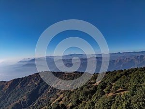 Expansive hilltops and mountain ridges with floating clouds in the Shivalik range of mountains, Mussoorie, Uttarakhand, India.