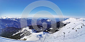 Expansive snowy mountain panorama under a clear blue sky.