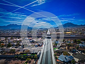 Expansive view of suburban Las Vegas with an overpass, mountains and airplane contrails in the sky