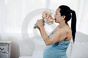 Expectant Asian pregnant Anticipated Mother with blooming Flowers branch in Her white Bedroom photo