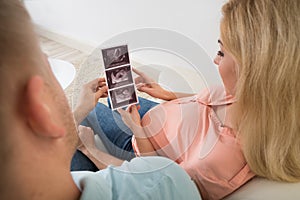 Expectant Couple Looking At Ultrasound Scan Report