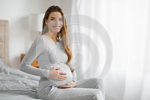 Expectant mom smiling on bed