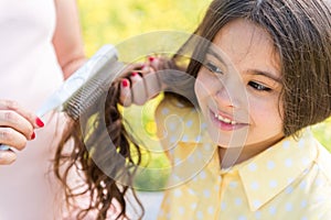 Expectant mother combing hair of her kid